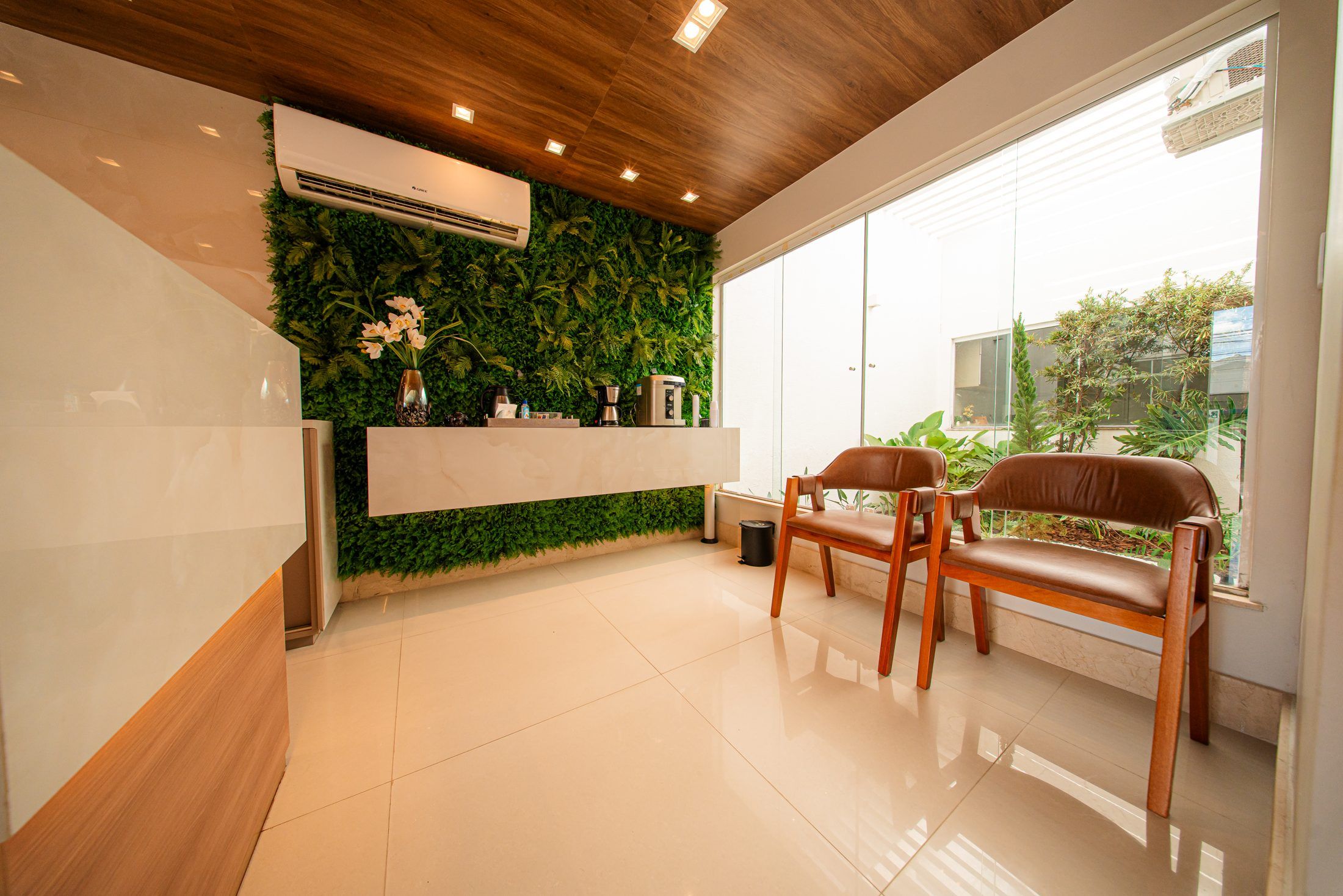 Área de espera da ORTHOESP Dental Studio com jardim vertical e luz natural